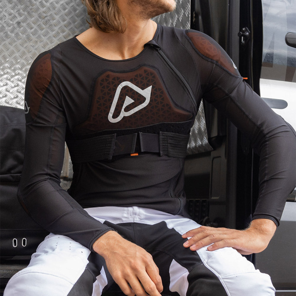 Black armored body shirt on person, showing front logo, chest straps, and sleeves.