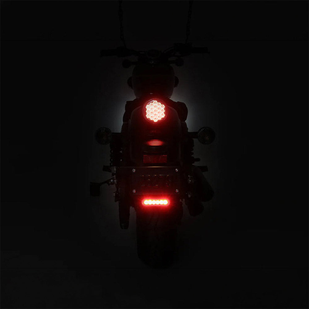 Auxiliary brake light on motorcycle, red LED glow on rear plate area, black housing