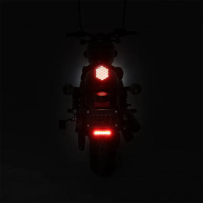 Auxiliary brake light on motorcycle, red LED glow on rear plate area, black housing