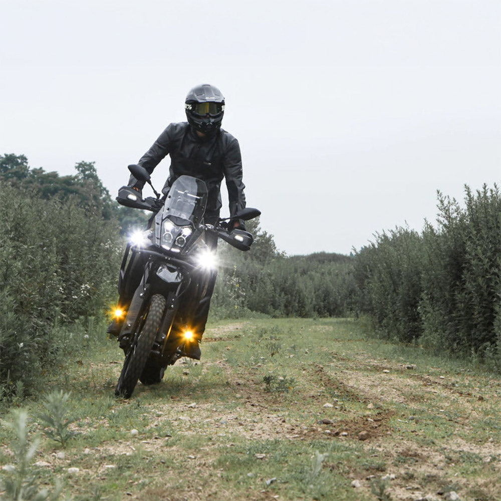 Black auxiliary LED light pods on motorcycle front, lights shining during outdoor ride