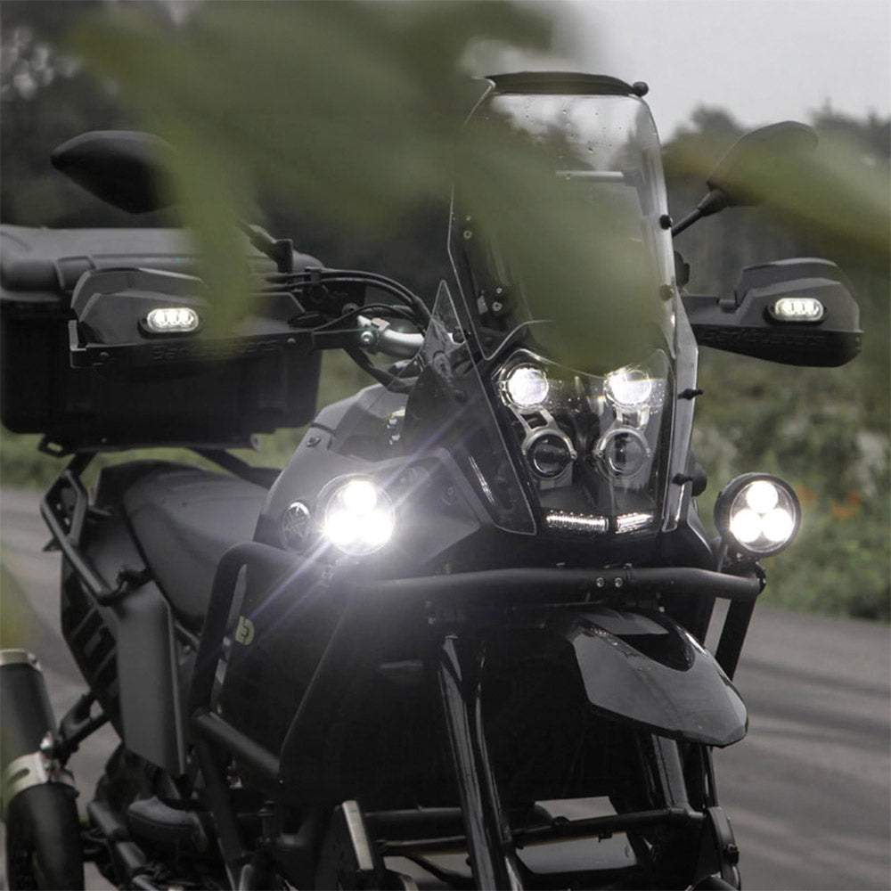 Black auxiliary LED light pods on a motorcycle front, spotlights glowing