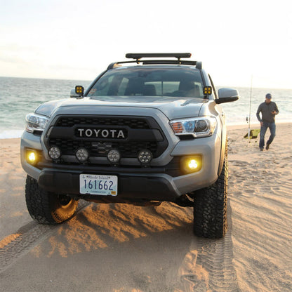Black auxiliary LED light pods on an off-road SUV grille area, lights glowing