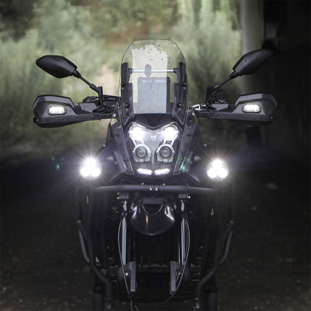 Black auxiliary LED light pods emitting bright beams on a motorcycle front view