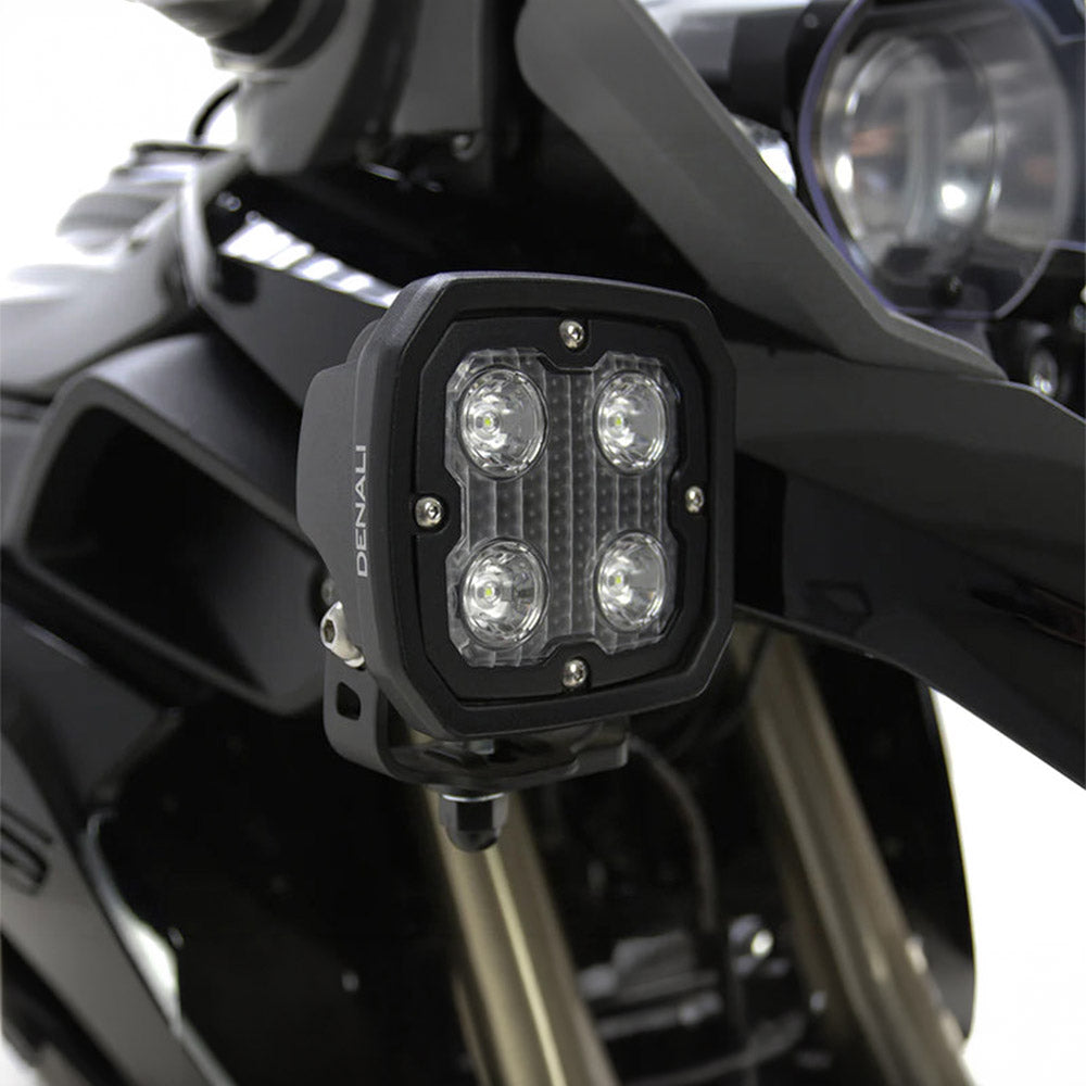 Black LED light pod with four lenses, mounted on vehicle