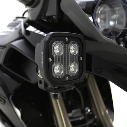 Black LED light pod with four lenses, mounted on vehicle