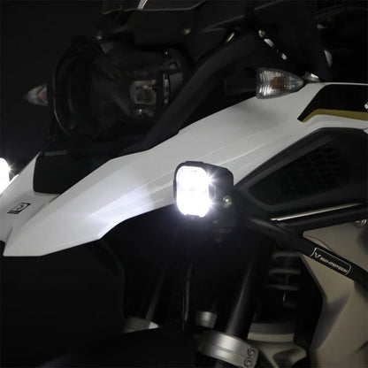 Black driving light pod on motorcycle, bright LED glow with clear lens