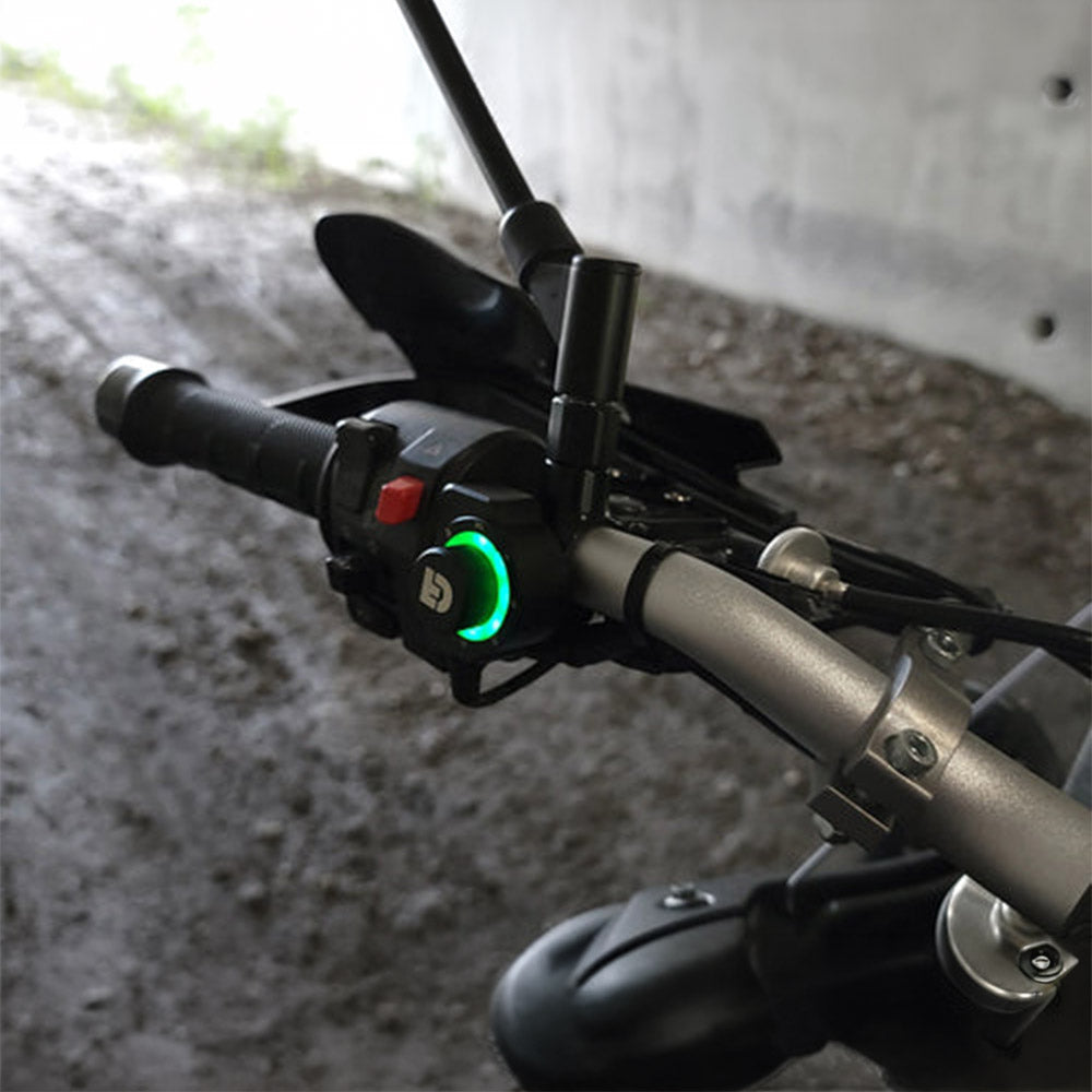 Black DialDim controller with green-lit dial ring on motorcycle handlebar