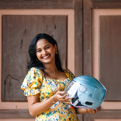 Aqua blue motorcycle helmet held by a woman with wave graphic on the shell