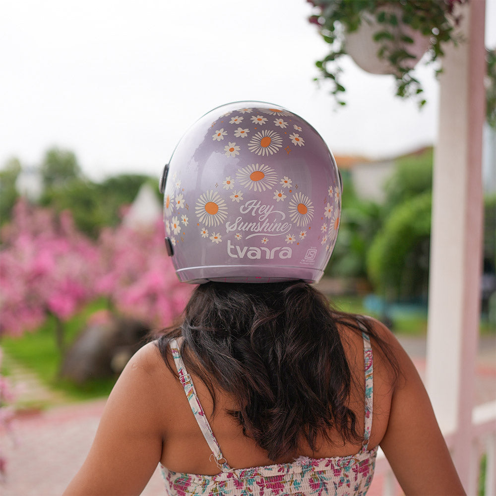 Lilac motorcycle helmet outdoors with daisy graphics and 'Hey Sunshine' design