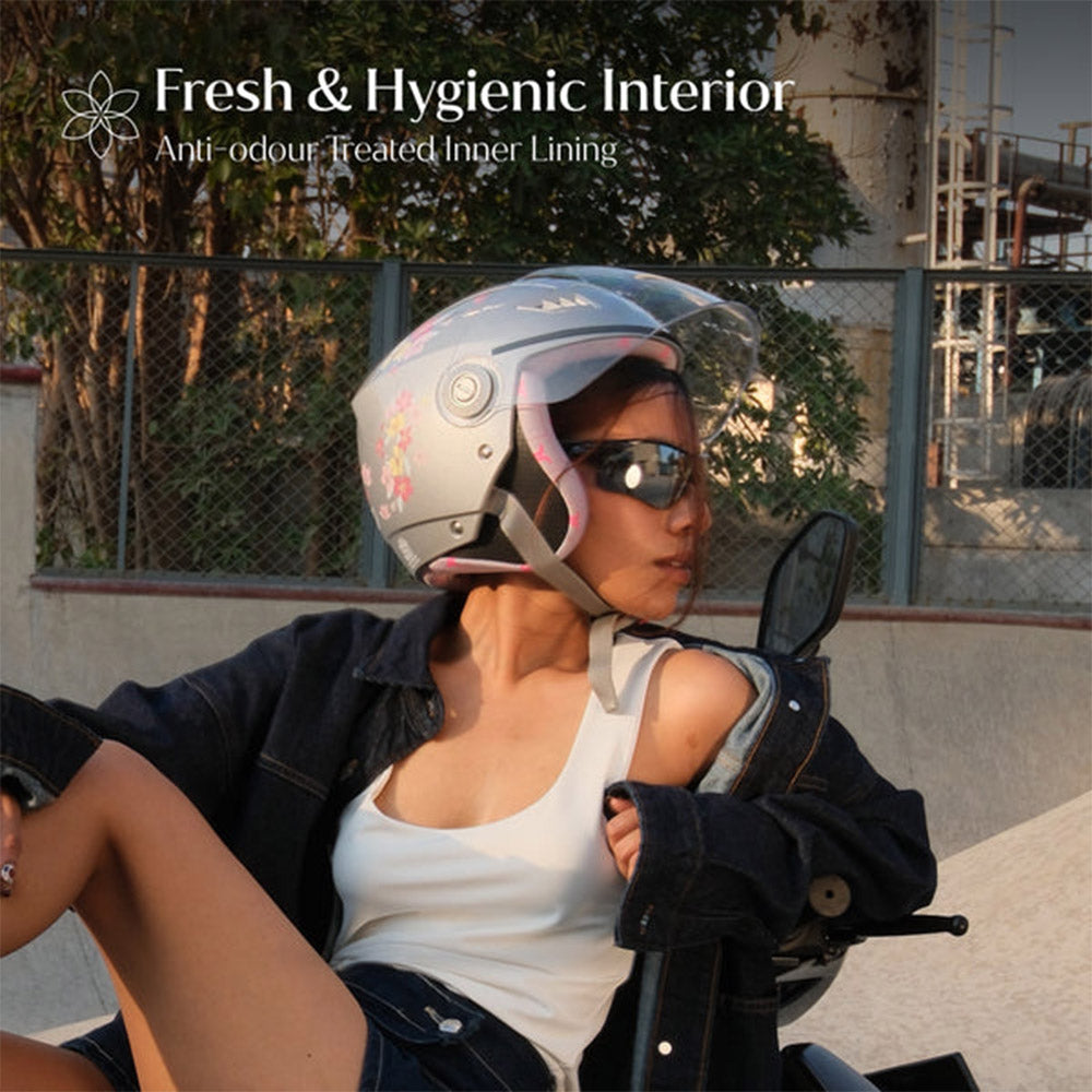Woman wearing gray-silver motorcycle helmet with clear visor and floral artwork