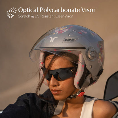 Woman wearing gray-silver motorcycle helmet with clear visor and floral blossom design